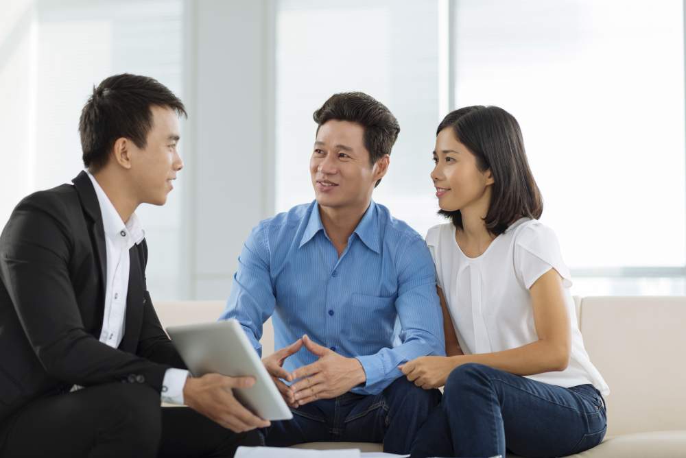 Chuyên viên tư vấn bất động sản trao đổi với khách hàng bên mô hình nhà đất